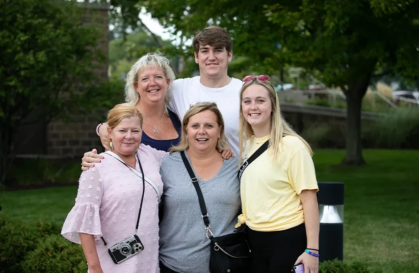 A family of five people poses outside for a group photo.