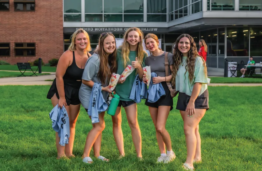 A group of students smiling outdoors in front of the Wellness and 娱乐 Center.